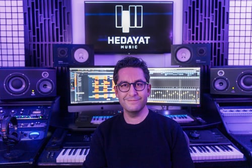 Hedayat, arrangeur/compositeur, devant du matériel de musique professionnel.